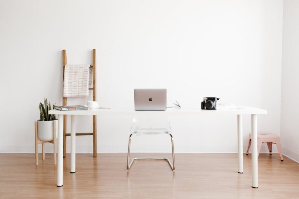 pexels-photo-8960464 Bright and minimalist home office setup with a white desk, laptop, and potted plant.